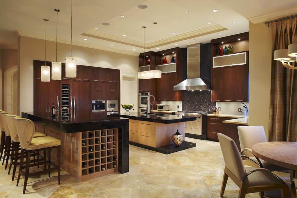 精致的厨房拥有深色染色木橱柜和夹在绝对黑色花岗岩台面和平台中的早餐岛。它还有一个厨房柜台，与软垫椅对齐，并配有酒柜。