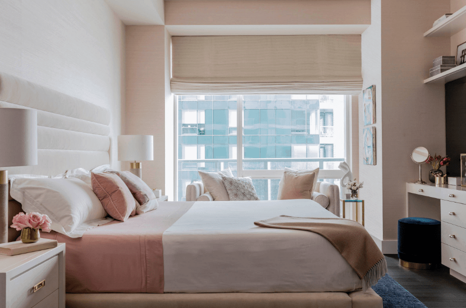 一扇覆盖着罗马窗帘的通高玻璃窗照亮了这间浅粉色的主卧室。它包括一个横跨簇绒床的坐角。