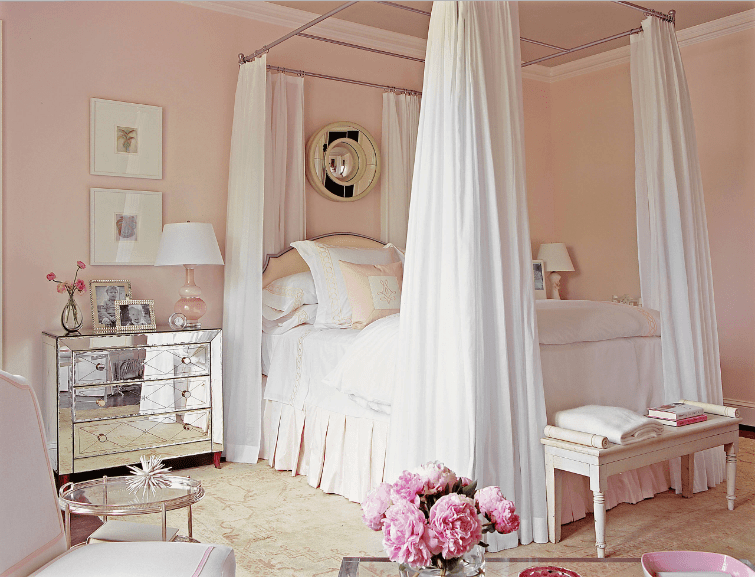 华丽的主卧室展示了一张天篷床和一张木凳。它还包括一个带镜子的床头柜，上面有一个可爱的台灯和装饰品。