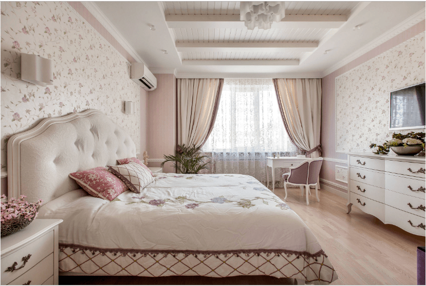 迷人的主卧室以碎花墙纸和托盘天花板为重点。它包括一个簇绒床，面对可爱的衣柜抽屉与床头柜相匹配。