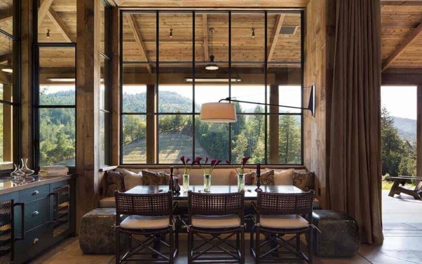 嵌壁式木凳后面的大窗户为木制餐桌带来了充足的自然光线，餐桌上的竹椅靠背是柳条编织的，座椅顶部有白色靠垫。