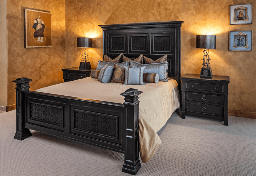 这是一间非常简单但引人注目的卧室，深色木床架与床头抽屉和上面的深色台灯完美搭配。墙壁的浑浊图案和单调的地毯与墙上的宗教艺术品形成了平衡。