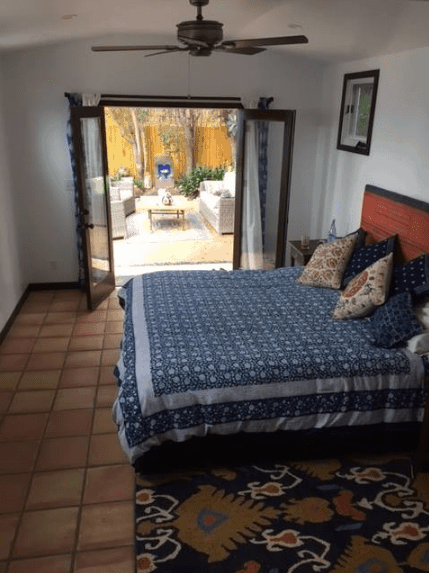一个小而方便的卧室，通过通往房子外面的门来平衡其缺乏的地板空间。砖色的陶土地板也给人一种更宽敞的错觉，而地毯和床罩上的图案为西班牙式卧室提供了特色。