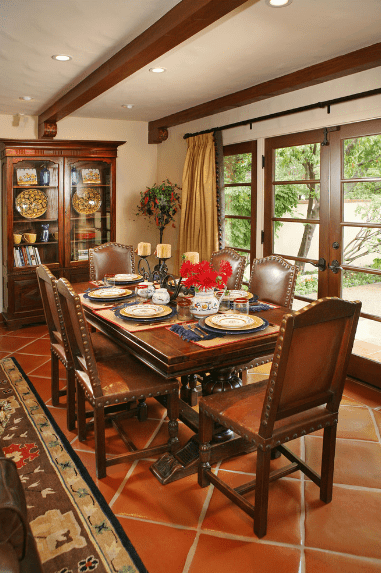 带有铁钉的深棕色皮革餐椅与木桌、法式橱柜和天花板上裸露的木梁形成了共同的色调。法式门也用深色木材镶边，使私密的西班牙餐厅看起来更大。