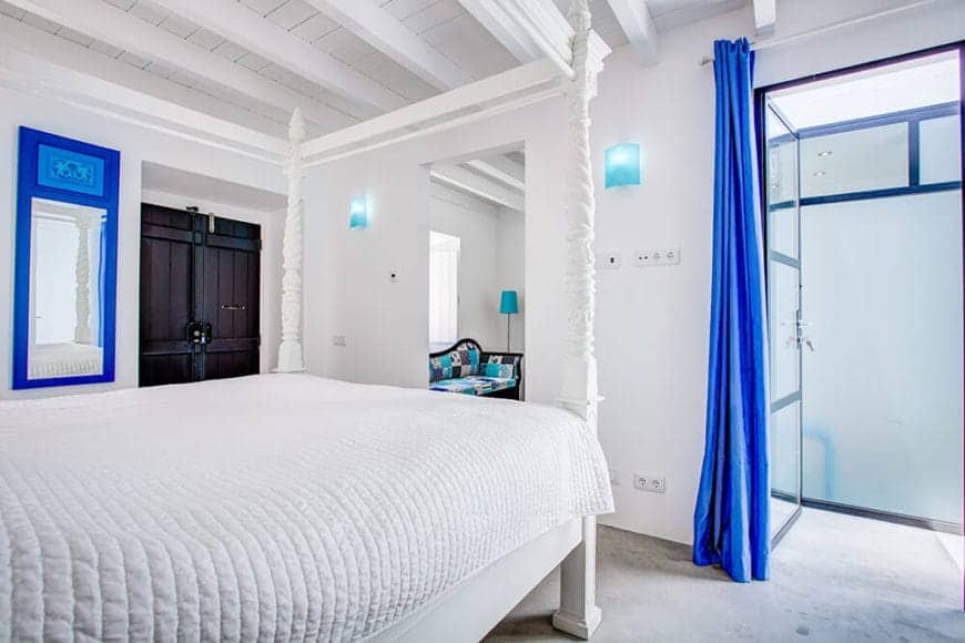一个非常明亮的房间，明亮的白色和明亮的蓝色。四柱床与裸露的天花板木梁是很好的搭档。古董木门的附加细节使这个房间具有明显的西班牙特色。