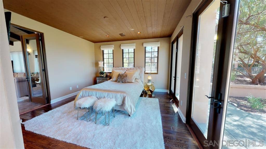 通风开放的西班牙卧室，由于其三扇落地窗和两组玻璃门，与地板和吊顶完美匹配。房间的特色是白色的毛茸茸的地毯，与白色床脚的两把椅子相匹配。