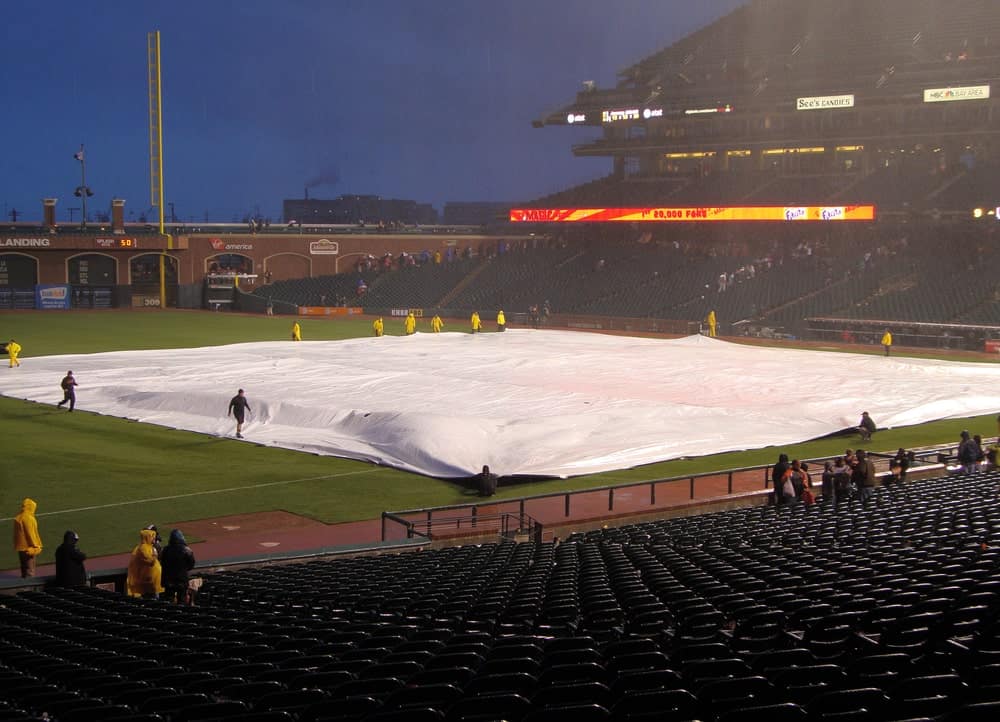当比赛开始下雨时，工作人员用防水布覆盖内场。