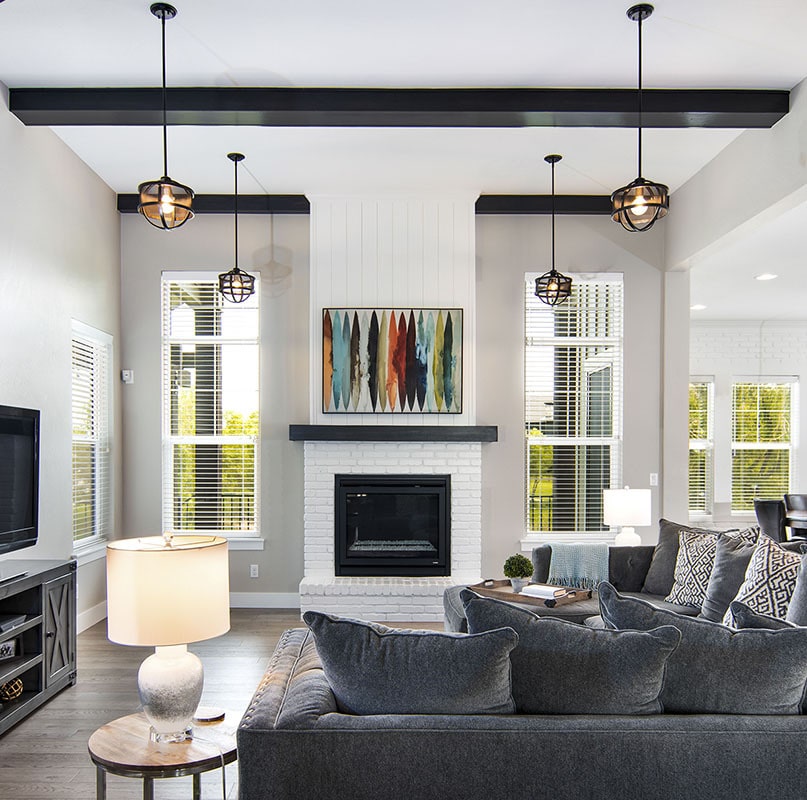 熟铁吊坠和白色砖砌壁炉上方的抽象画装饰着这间明亮通风的客厅。