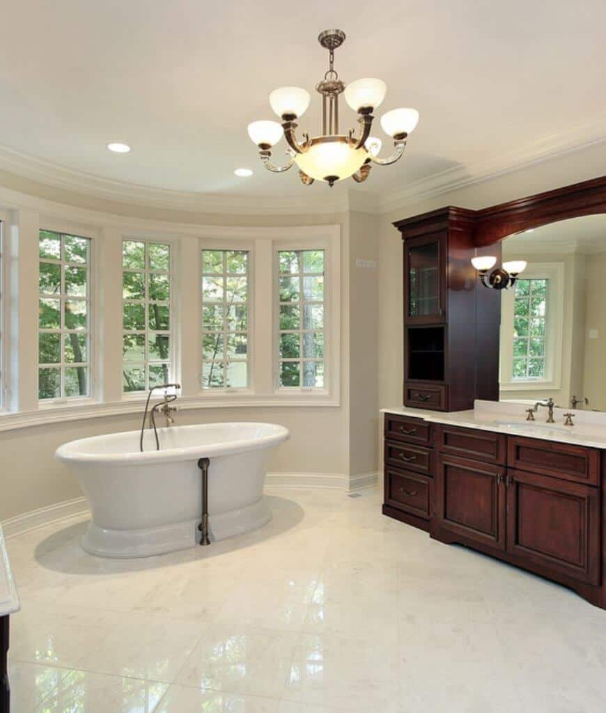 经典的主浴室配有木制洗手台和独立浴缸，以及迷人的吊灯，照亮了该地区。