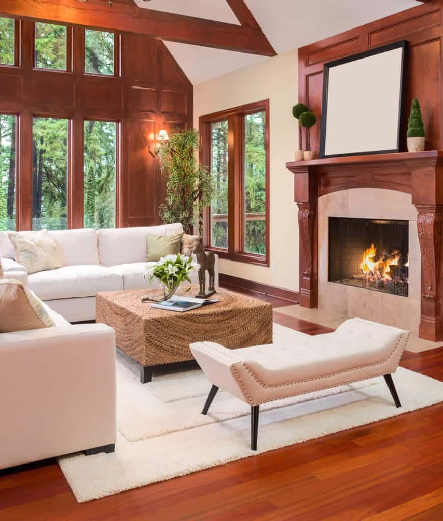 舒适的客厅，红木墙和壁炉与硬木地板互补，上面有白色蓬松的地毯。它包括白色分组组和一个簇绒长椅搭配柳条咖啡桌。