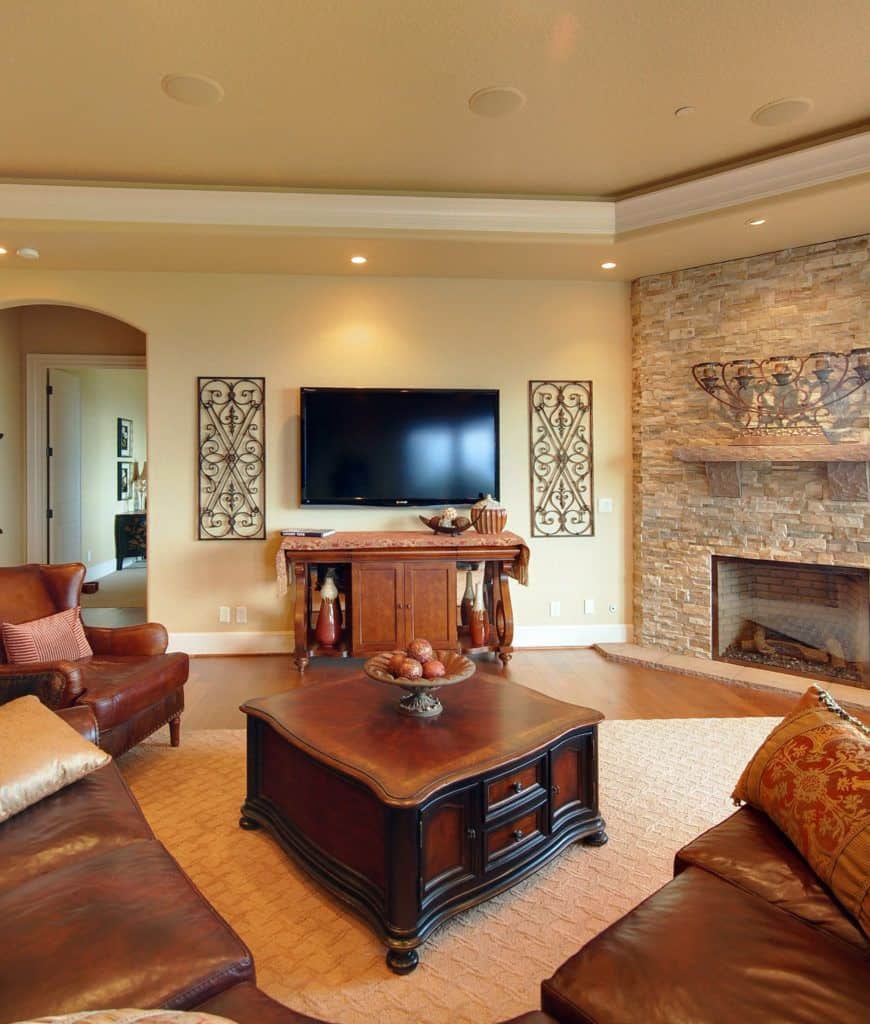 黄色的客厅装饰着华丽的墙壁艺术突出电视在中间。它有一个皮革后卫椅子和木茶几周围弯截面米色纹理的地毯。