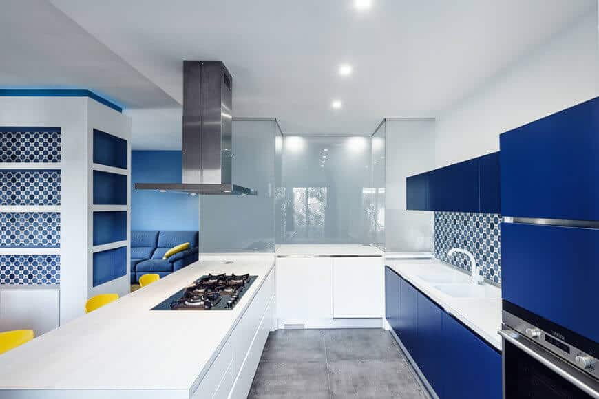 以蓝白为主题的厨房。后挡板与灰色瓷砖地板一起看起来很时尚。