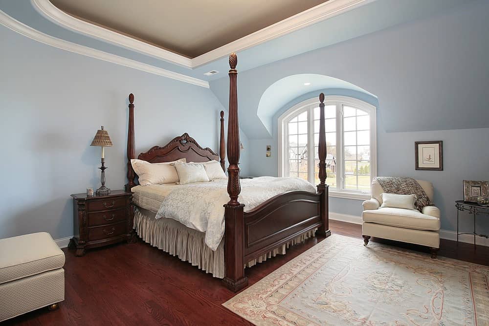 这间主卧室的特色是蓝色的墙壁和红色的硬木地板，上面铺着漂亮的地毯。