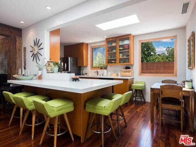 这是一间舒适而紧凑的亚洲风格厨房，硬木地板与带有白色台面的木质厨房半岛融为一体。它们与白色的墙壁融合在一起，白色的墙壁上装饰着各种亚洲艺术品。