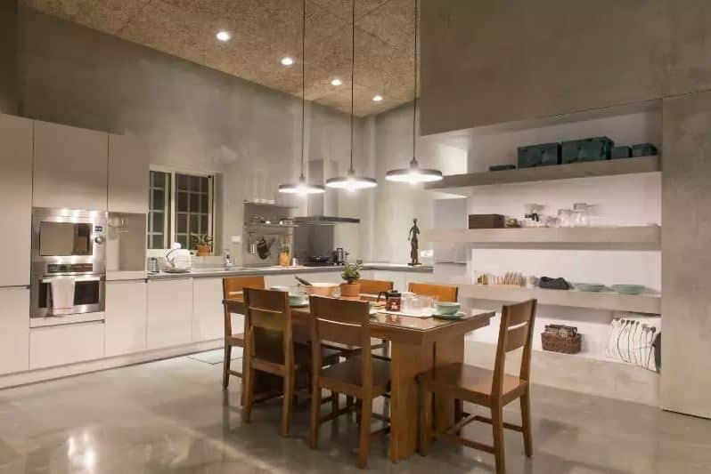 这种亚洲风格和工业风格元素之间的简单融合形成了这个可爱的设计。它有灰色的混凝土墙和内置的混凝土架子。还有一个软木塞状的木质天花板，带有嵌入式灯，以增强吊灯的灯光，照亮白色l形厨房。