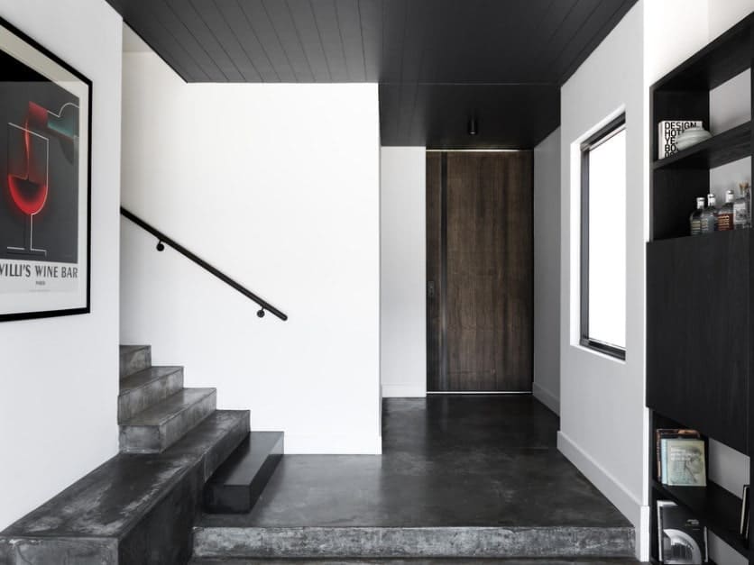 这个门厅以白色的墙壁和黑色的地板以及黑色的天花板为特色。