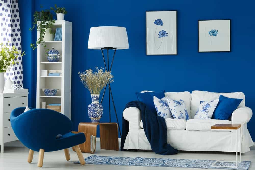 蓝色的客厅配有配套的蓝色椅子和白色沙发上的抱枕。