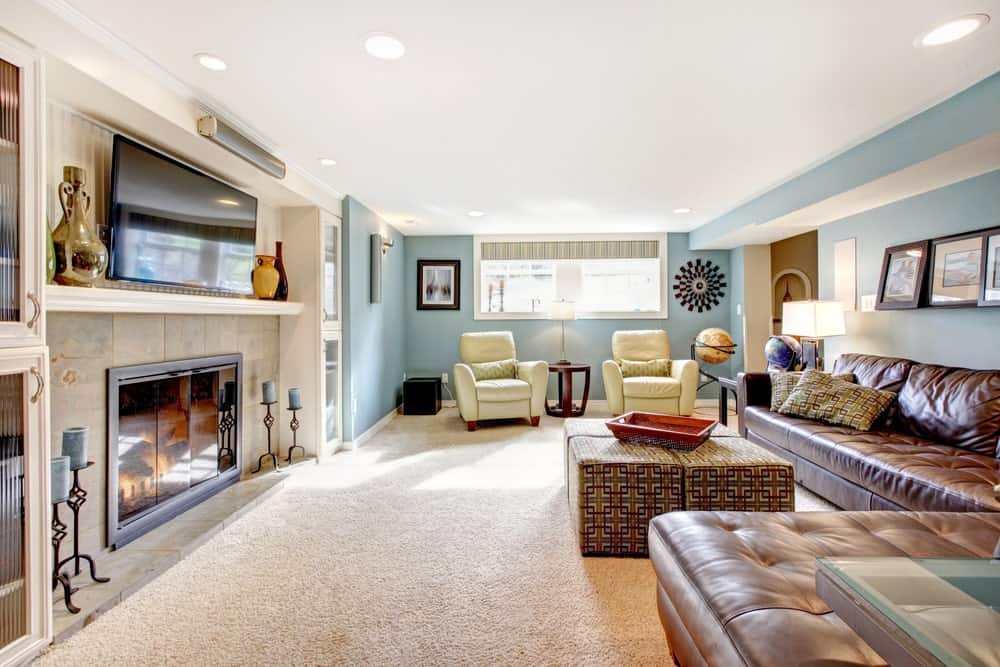 大客厅设有地毯地板和天蓝色的墙壁。房间提供一套棕色皮革沙发和一个壁炉，壁炉上有一台电视。