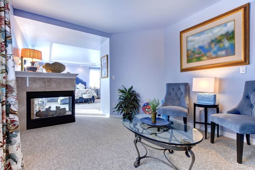 带独立客厅的主套房。它以蓝色为主题，蓝色的墙壁和一对配套的椅子。有一张精致的玻璃桌和一座壁炉。