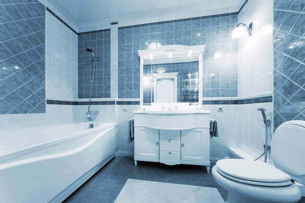 小主浴室设有浴缸和淋浴组合，以及一个水槽。蓝灰色的地板和墙壁使这个房间看起来很漂亮。