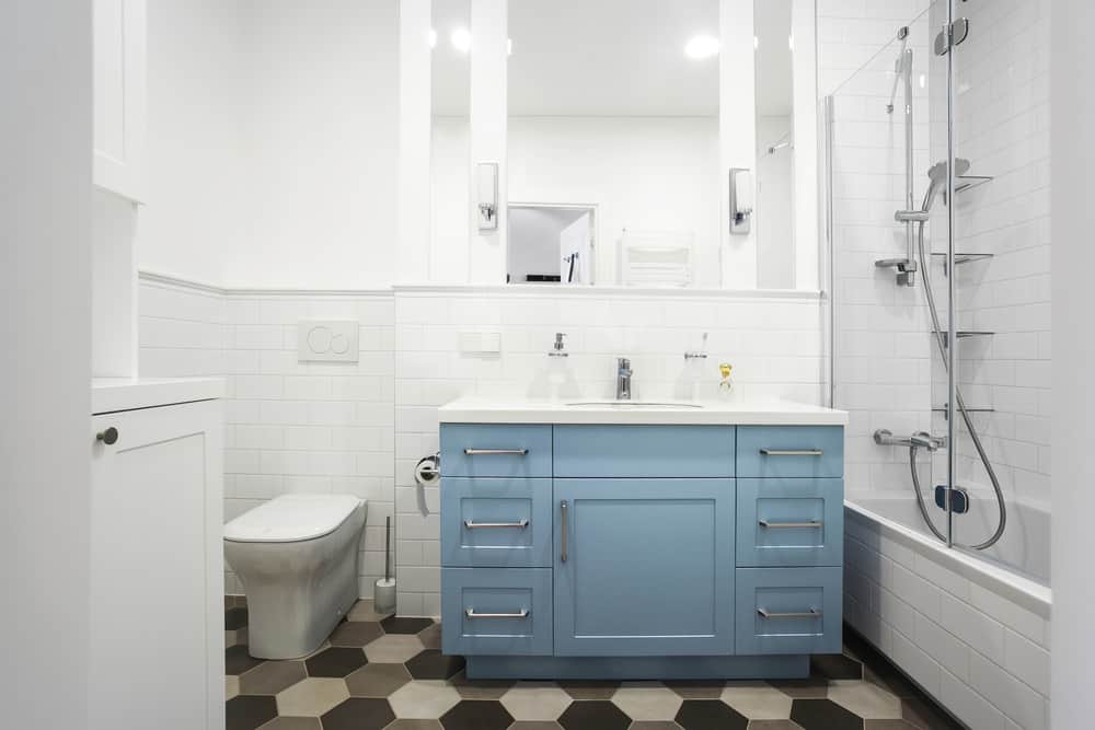 小型主浴室设有时尚的瓷砖地板，淋浴和浴缸组合以及蓝色水槽柜台。