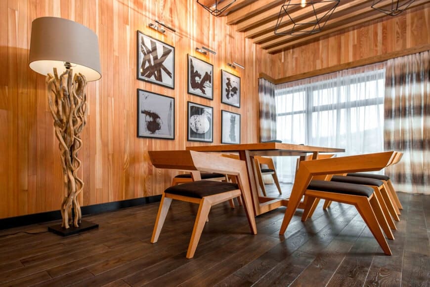 餐厅区设有时尚的餐桌和椅子，周围环绕着棕色木墙和露出横梁的天花板。