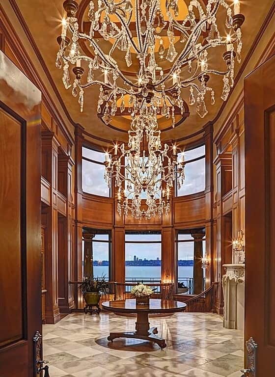 这个宏伟的门厅提供优雅的瓷砖地板，在高高的天花板上悬挂的大吊灯下面的中间有一个圆形的餐桌。