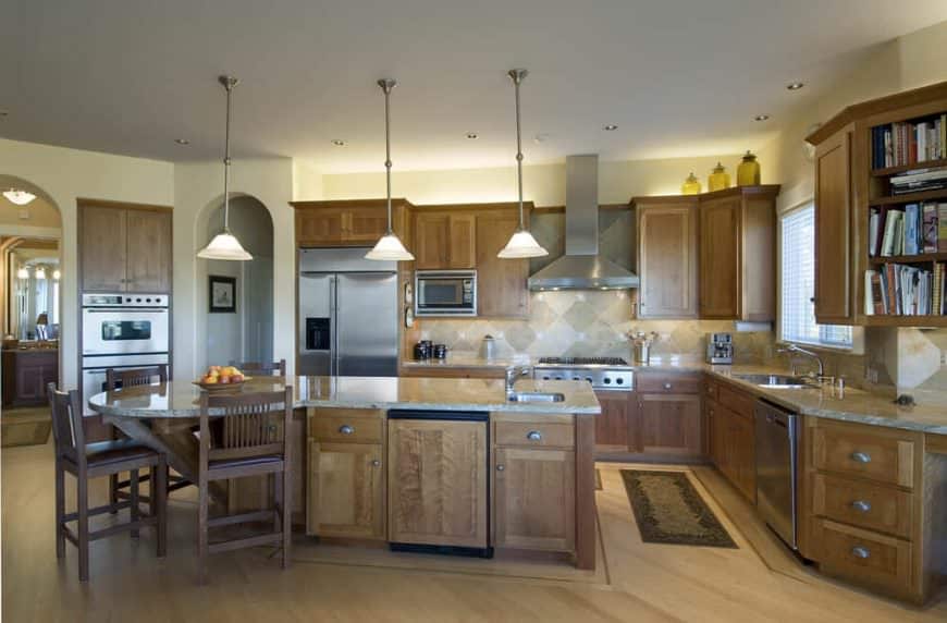 宽敞的厨房设有由三盏吊灯照明的早餐吧空间。厨房也有棕色的橱柜和厨房柜台。