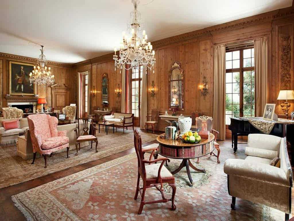 宽敞的棕色客厅设有多个高档座椅，角落里有一架黑色钢琴和一座壁炉。这个区域由两个迷人的枝形吊灯照亮。