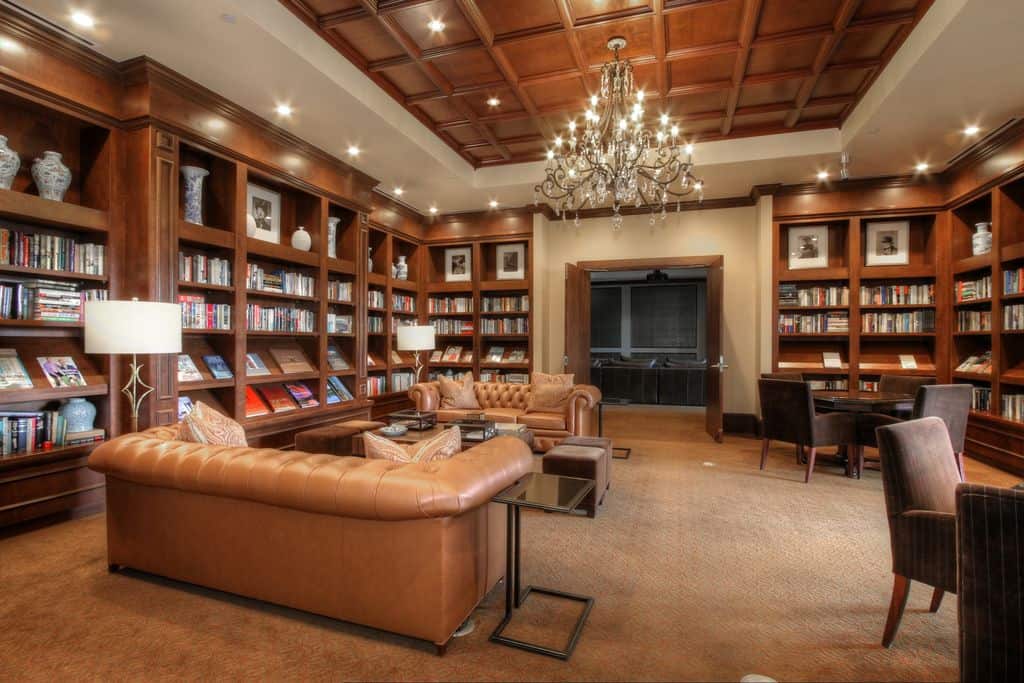 宽敞的起居区设有棕色沙发和多个棕色内置书架，里面摆满了书籍。该区域的地板上覆盖着棕色地毯。