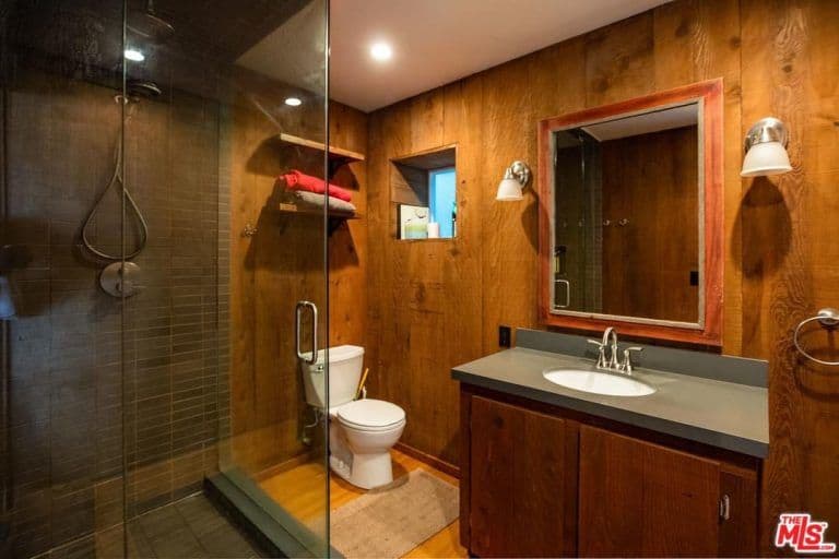 棕色的主浴室设有一个由一对壁灯照明的水槽和一个步入式淋浴房。