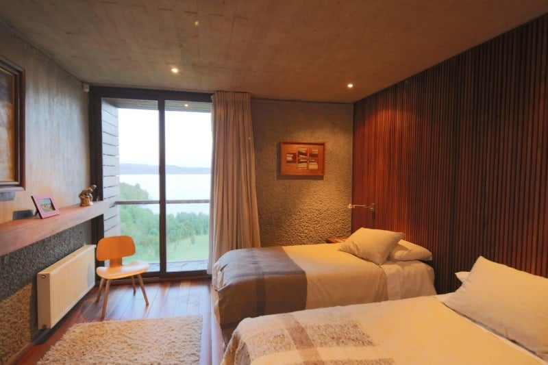 这间客厅提供两张床和一面棕色的墙以及硬木地板。