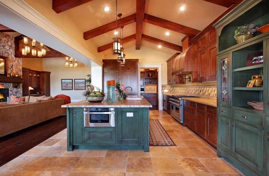 工匠风格的厨房以教堂天花板为特色，暴露的木梁与橱柜融为一体。中央岛台有一个内置烤箱，里面有木制抽屉和橱柜，表面是绿色的。