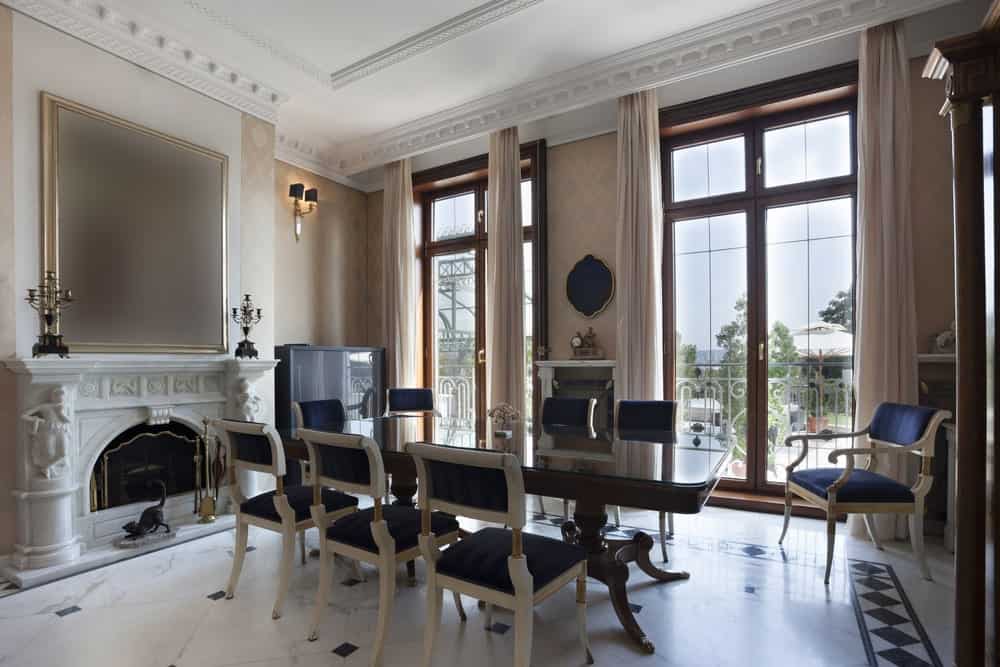 优雅的餐厅与白色大理石地板和全高度玻璃覆盖着纯粹的窗帘。它有一个长方形的餐桌用优雅的深蓝色的椅子。