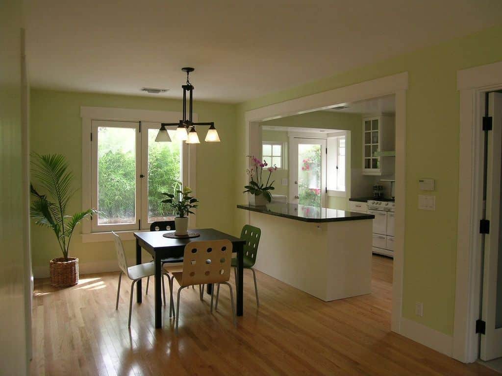 一间带餐厅的厨房，室内有盆栽植物，四周环绕着绿色的墙壁。房间还设有硬木地板。
