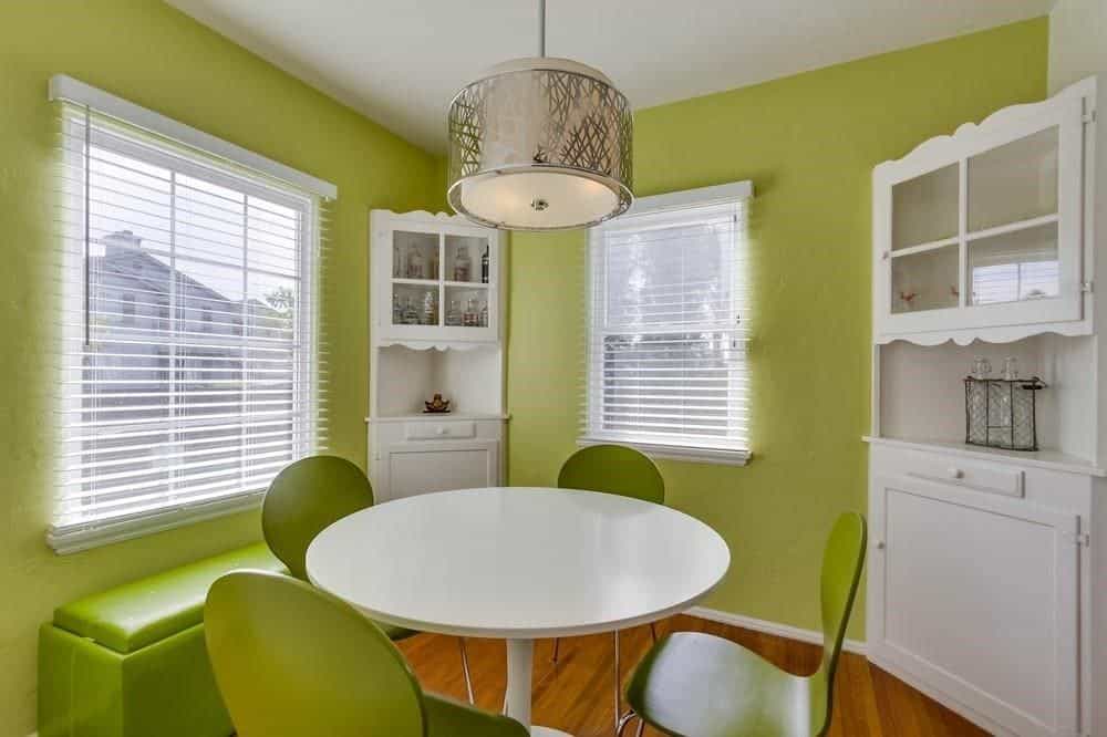 小餐厅区有绿色的墙壁和绿色的长凳，白色的圆桌搭配绿色的椅子。