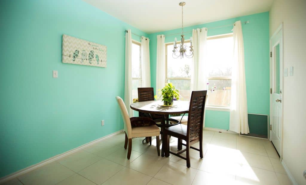 宽敞的厨房设有绿色墙壁和瓷砖地板，以及一个可供四人用餐的圆形餐桌。