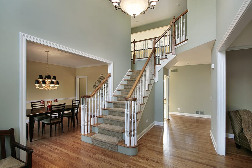 极简主义的门厅设有硬木地板和绿色墙壁，以及铺着地毯的楼梯台阶。