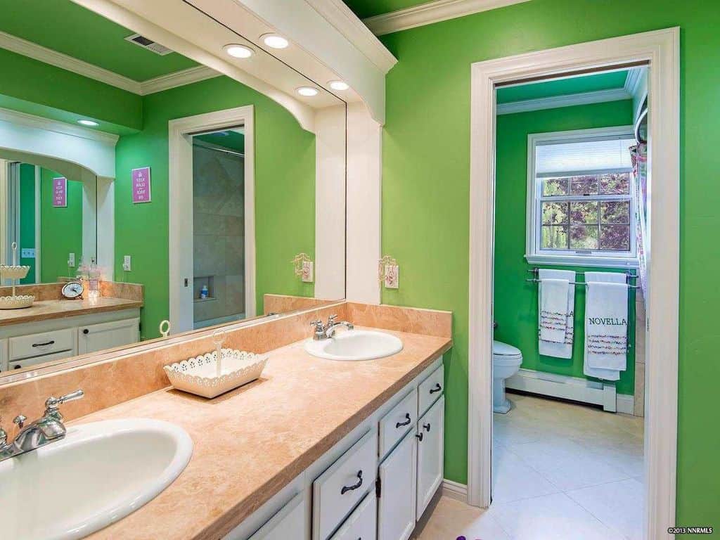 近距离看这个主浴室的双水槽，周围是绿色的墙壁。该房间还设有厕所区。