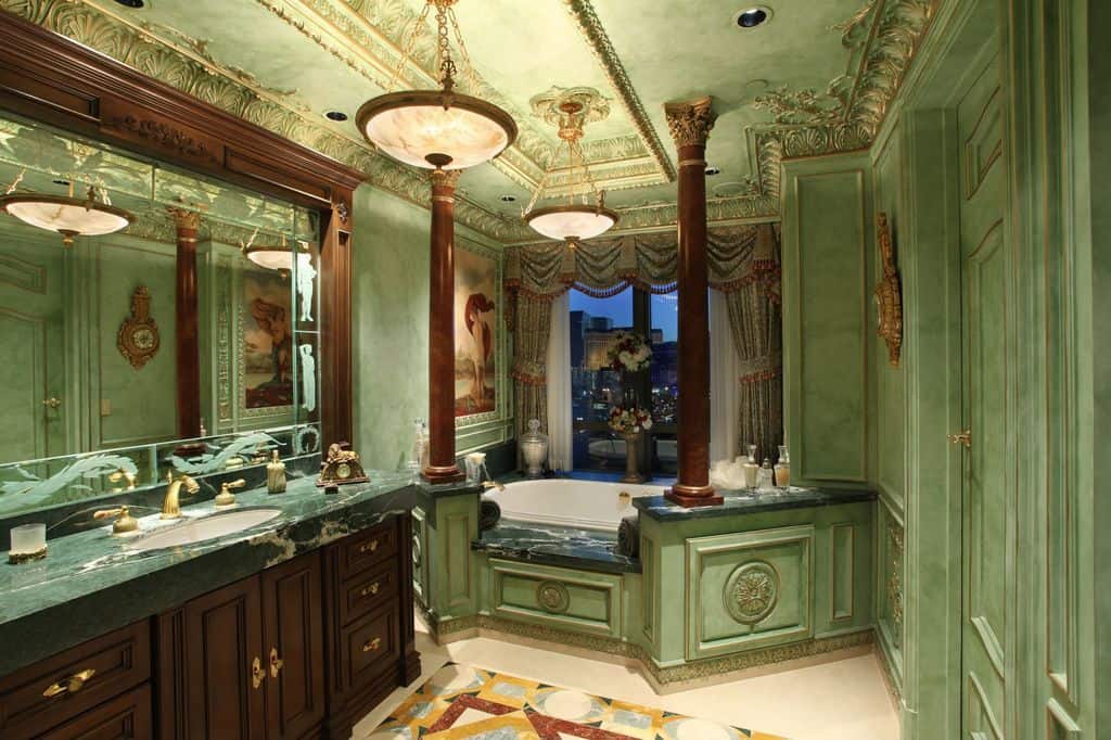 绿色的主浴室拥有一个浪漫风格的浴缸和一个非常优雅的天花板，由吊灯照明。