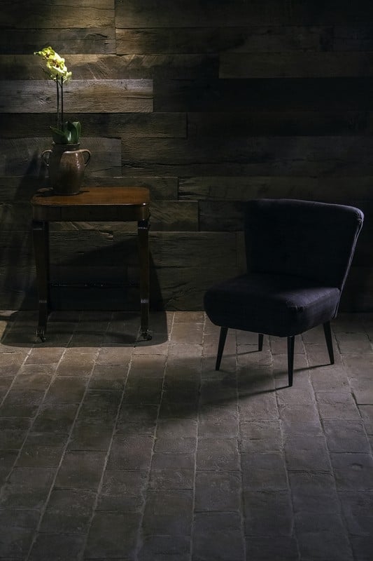 黑暗terracotta砖瓷砖地板和一把椅子上面还有一个小桌子。