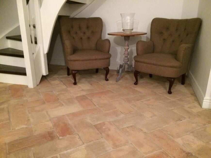 住宅的楼梯平台铺着浅色的赤陶瓷砖地板，中间有两把椅子和一张桌子。