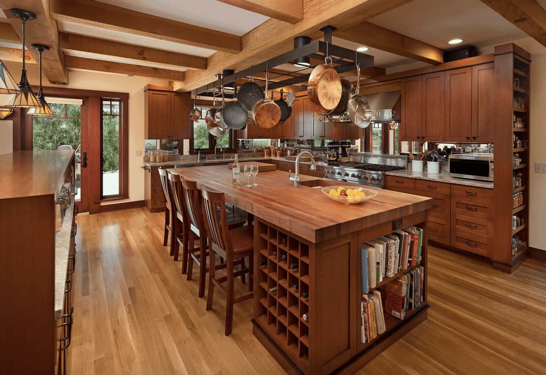 工匠厨房提供丰富的木质橱柜和一个黑色金属锅架，位于木制早餐岛，配有内置搁架和酒架小柜。