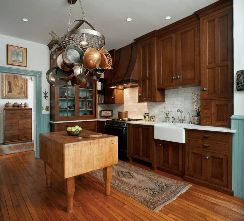 厨房里的木制柜台上有一个椭圆形的锅架，上面有深色的木橱柜和展示柜，上面有一个厨房滑道。