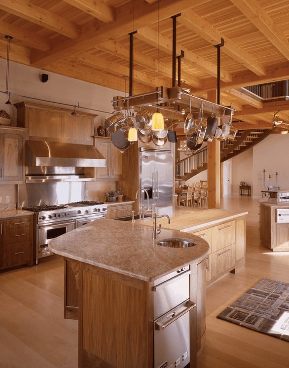 农舍厨房提供轻木橱柜和早餐岛，与硬木地板相辅相成。横梁天花板和锅架的木材元素的连续性创造了统一的外观。