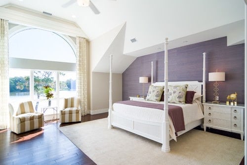宽敞的主卧室，硬木地板，白色地毯，还有一面紫色的墙。