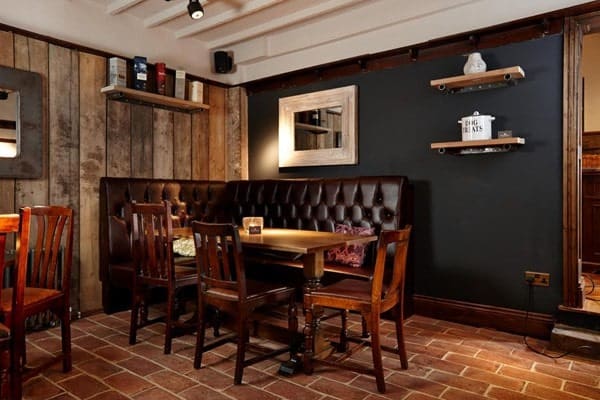 一个用餐区，有一个漂亮的沙发和一个优雅的餐桌，餐桌设置在回收的赤陶砖瓷砖地板上。