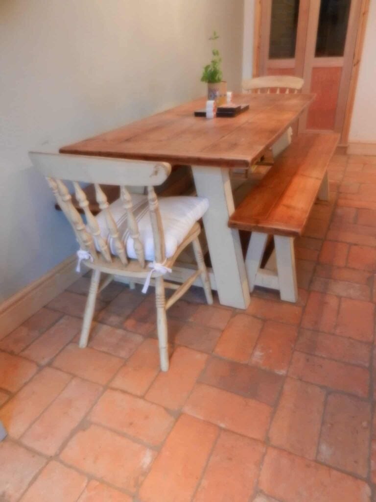 在陶土砖地板上放着一张长方形餐桌。