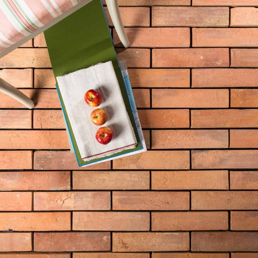 温暖的陶土瓷砖地板，上面有苹果靠近椅子。