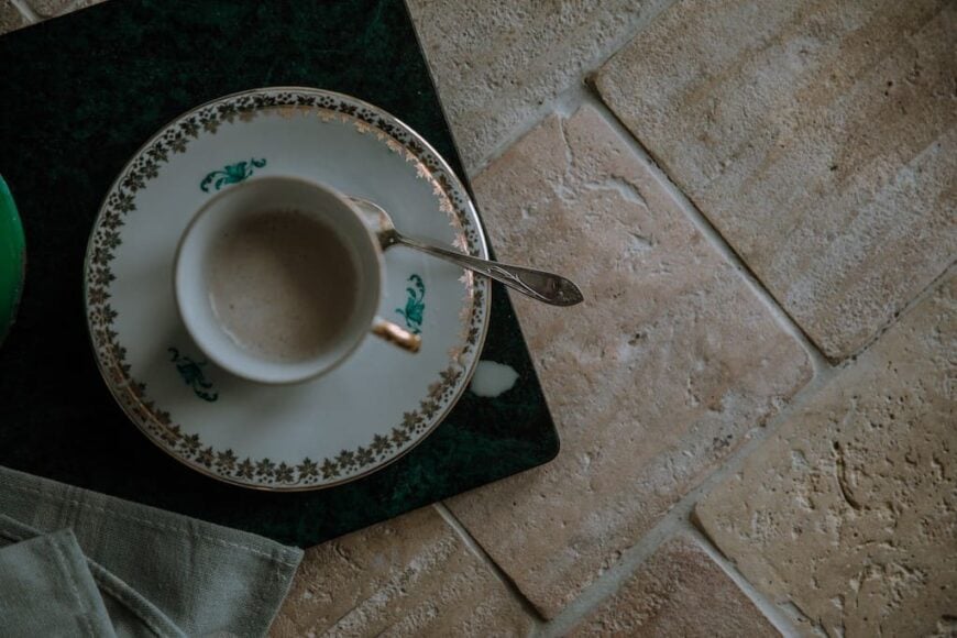 近距离观察这杯咖啡，它放在浅色陶土地板上的碟子上。